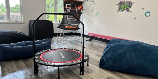 Indoor playroom with trampoline, basketball game, and bean bags.