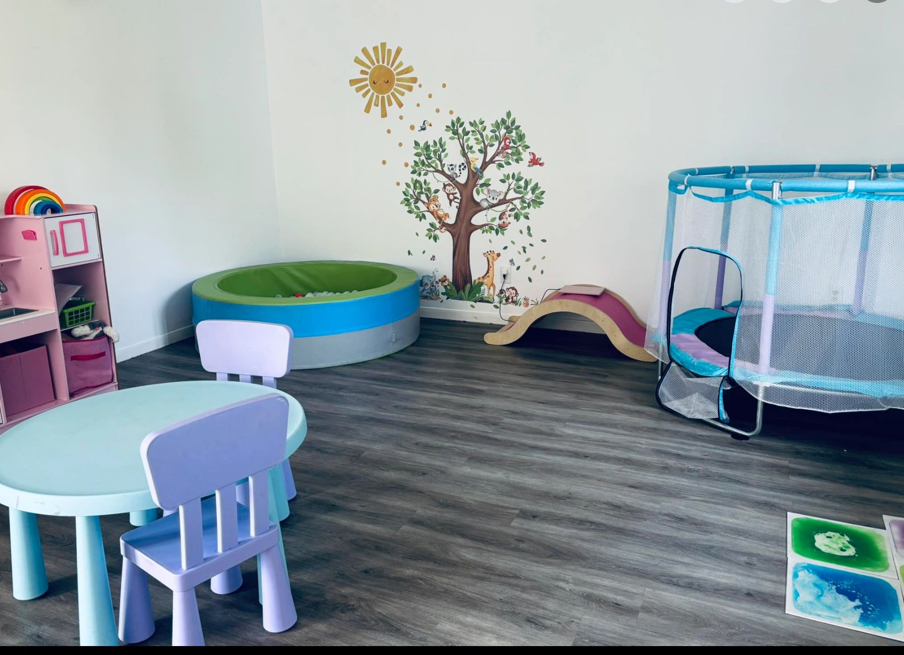 Bright and colorful kids' playroom with toys, a small table, and wall decals.