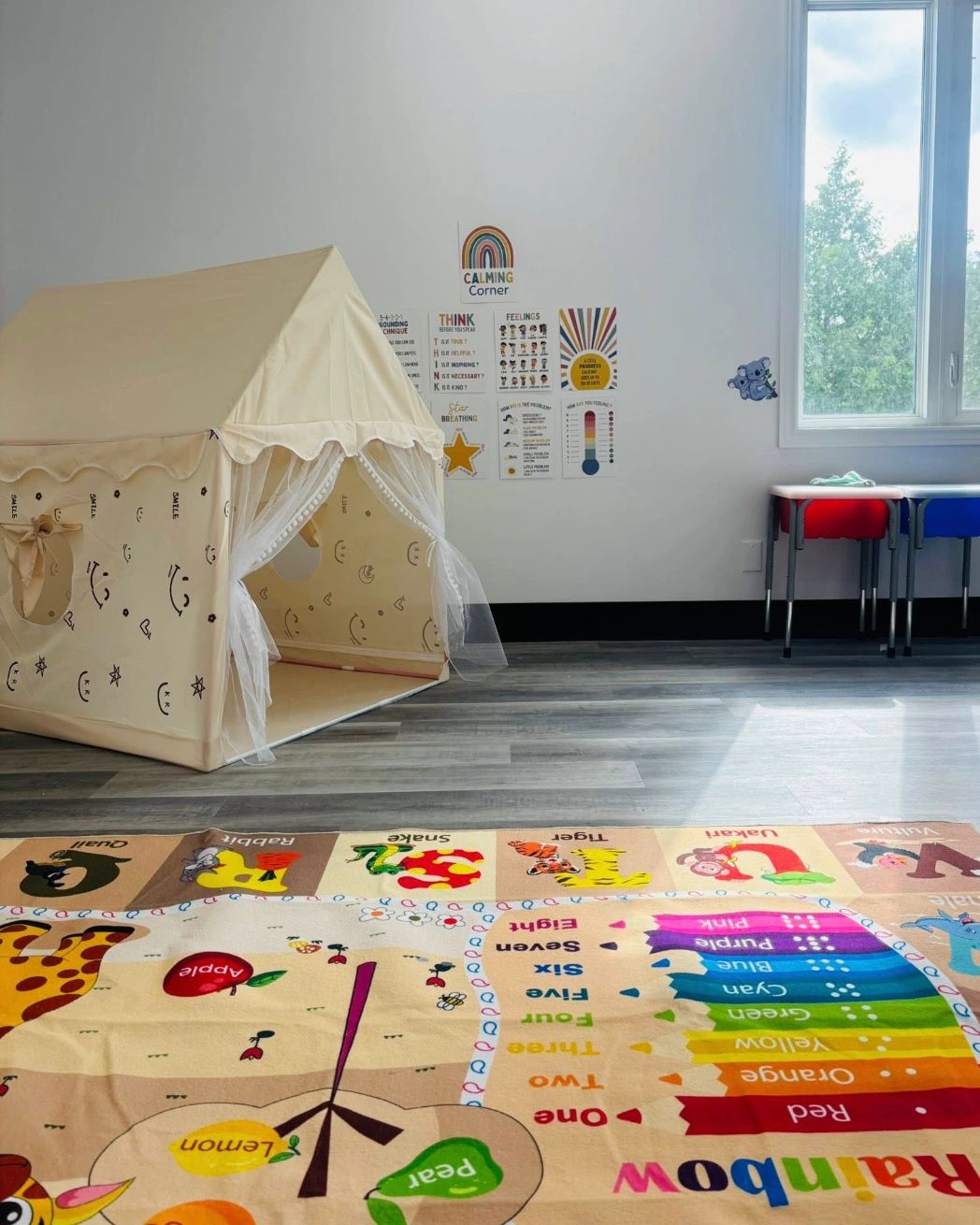 Colorful children's playroom with a tent, educational rug, and calming corner posters.
