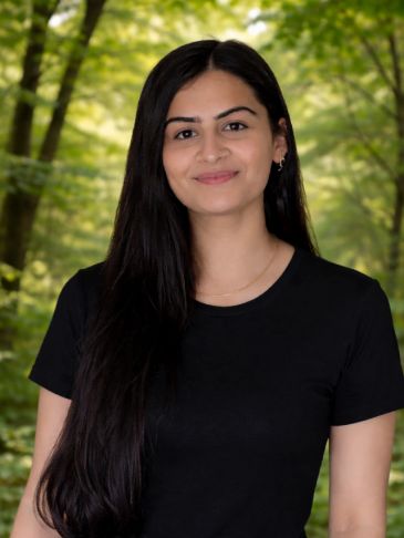 Young woman with long hair smiling in a forest.