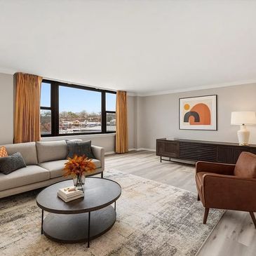 Bright modern living room with large windows and cozy seating.
