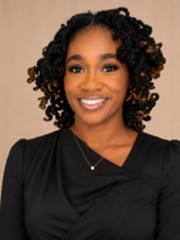 Smiling woman with curly hair in a black dress.