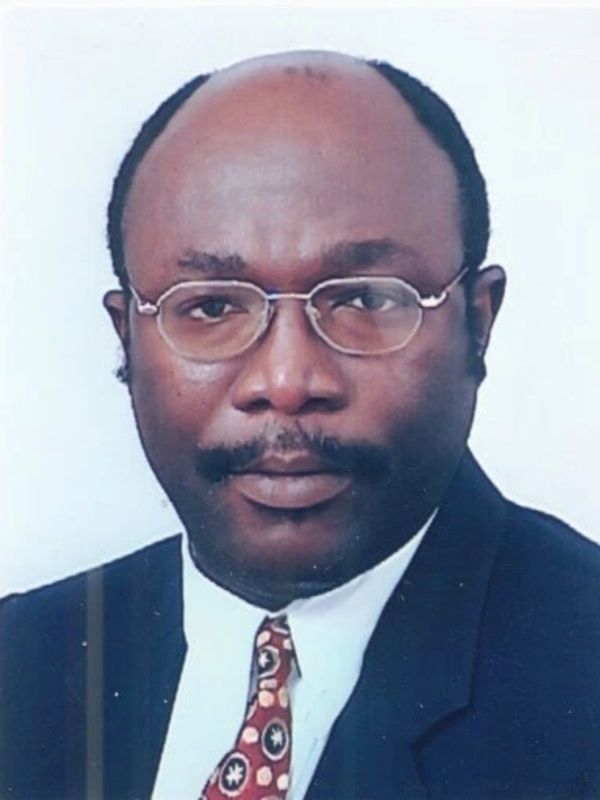 Portrait of a man wearing glasses, a suit, and a patterned tie.