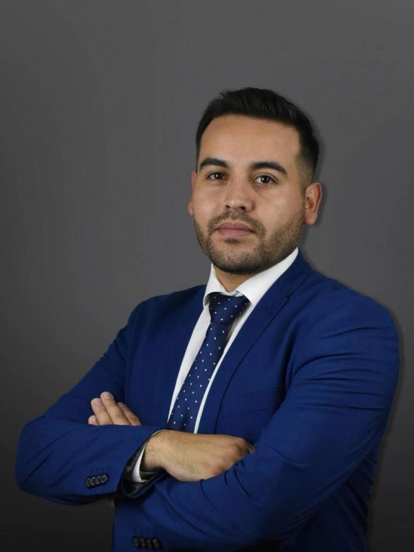 Man in blue suit with a confident expression and crossed arms.
