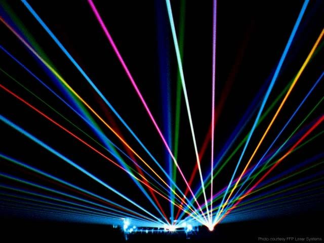 Colorful laser beams radiating from a stage in a dark setting.