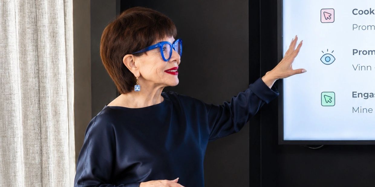 Woman in blue glasses presenting information on a screen.