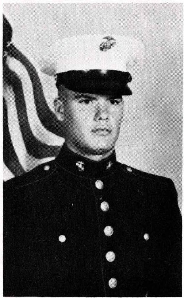 Young man in a US Marine Corps dress uniform with an American flag background.