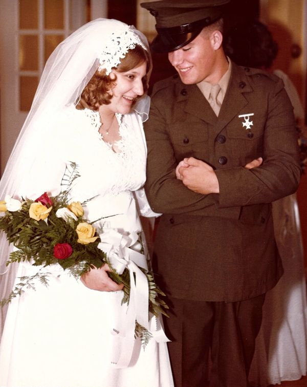 Bride and groom smiling on their wedding day, groom in military uniform.