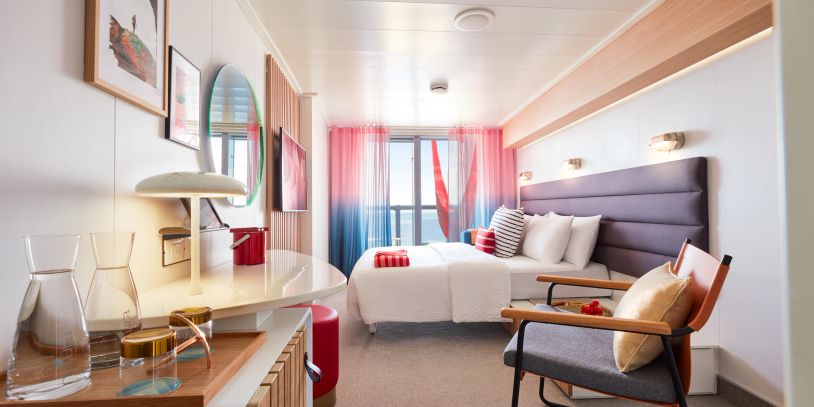 Bright, modern hotel room with ocean view and colorful decor.