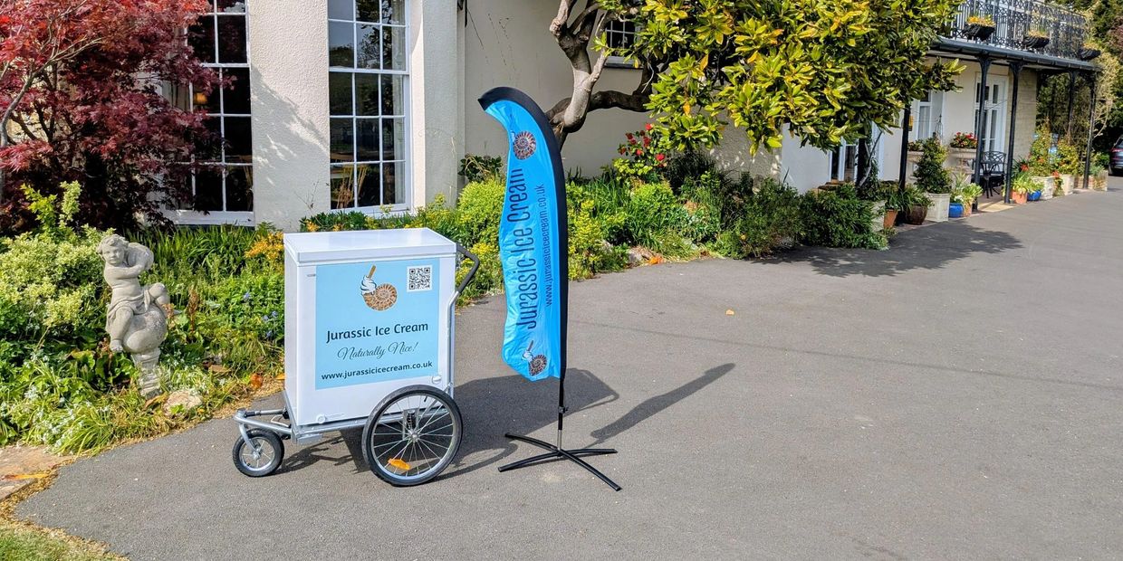 Jurassic Ice Cream cart and flag in a garden setting.