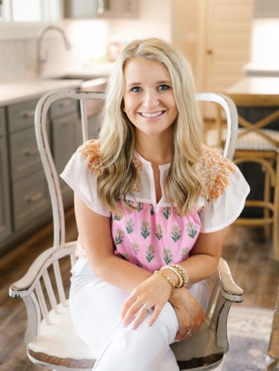 Smiling woman with blonde hair sitting on a chair.