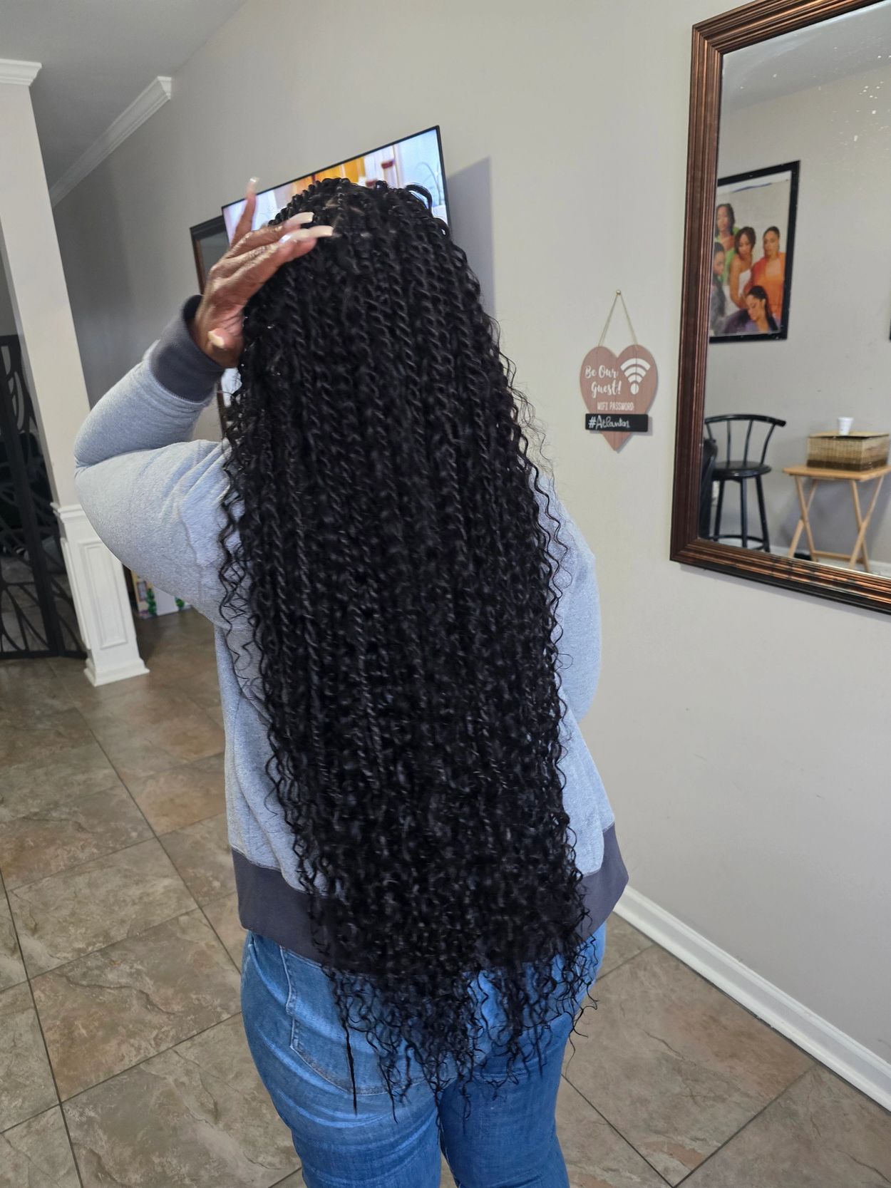 Person showing long, curly black hair from the back indoors.