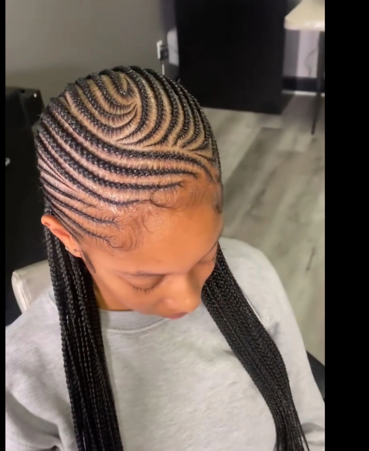 Intricately braided cornrows forming a swirl pattern on a woman's head.