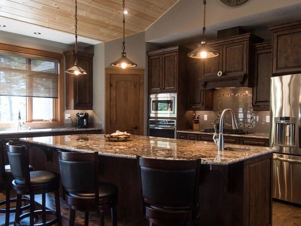 Luxurious kitchen with dark wood cabinets and granite island.