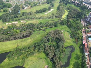 Aerial view of a lush golf course with trees and water features.
