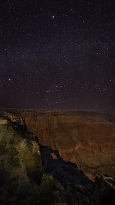 Starry night sky over a canyon landscape.