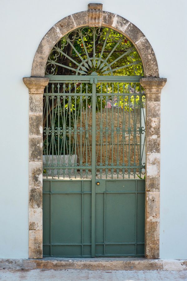 A green color iron gate to a garden