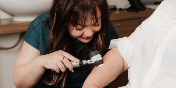 Doctor examining patient's arm with a dermatoscope.