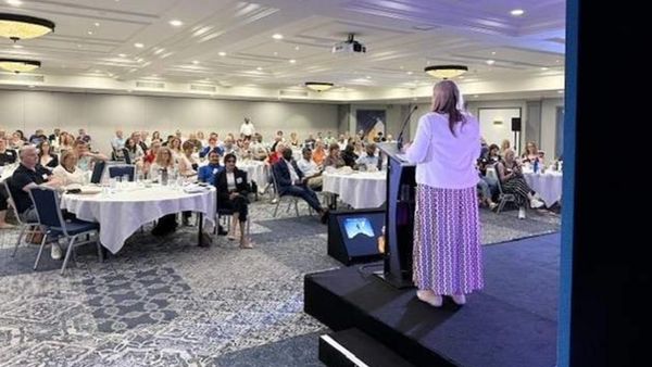 Woman speaking at a conference in front of an audience.