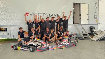 Team celebrates victory with go-karts in front of Victory Lane.