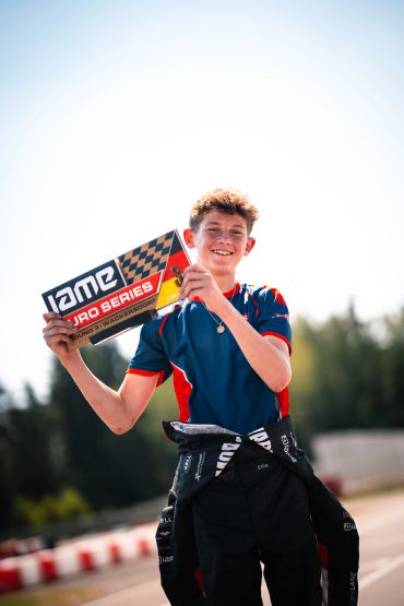 Young racer holding a trophy at a karting event.
