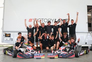 Karting team celebrating victory with trophies and karts.