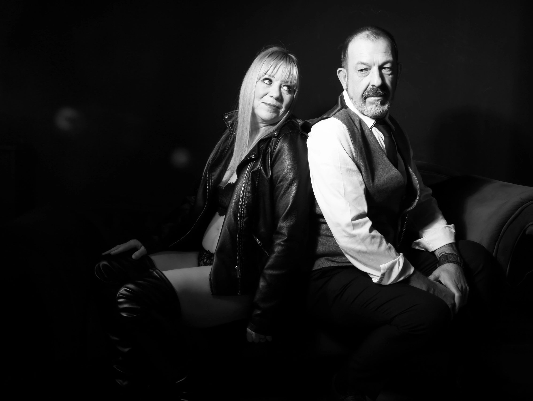 Black and white portrait of a stylish couple sitting back to back.
