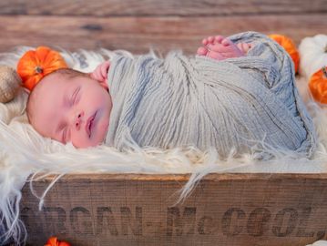 Newborn baby peacefully sleeping wrapped in a soft gray blanket.