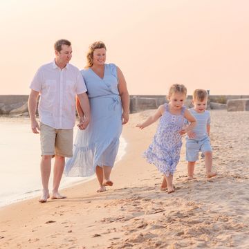 Family of four walking on the beach at sunset.