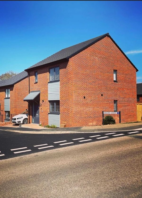Modern brick house on a sunny day with clear blue sky and a white car parked.
