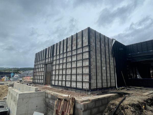 A building under construction with concrete blocks and metal framework on a cloudy day.