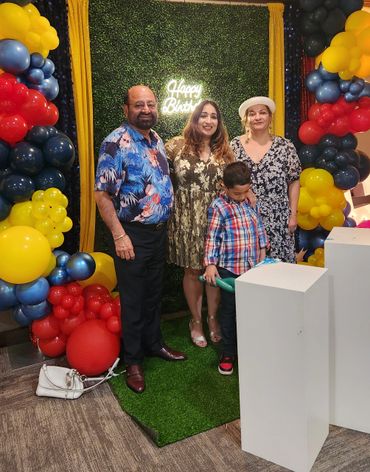 Family celebrating a birthday with colorful balloon decorations.