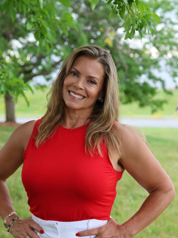 Smiling woman in a red sleeveless top outdoors.