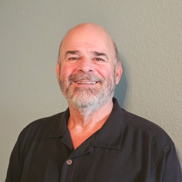 Smiling bald man with beard in black shirt.