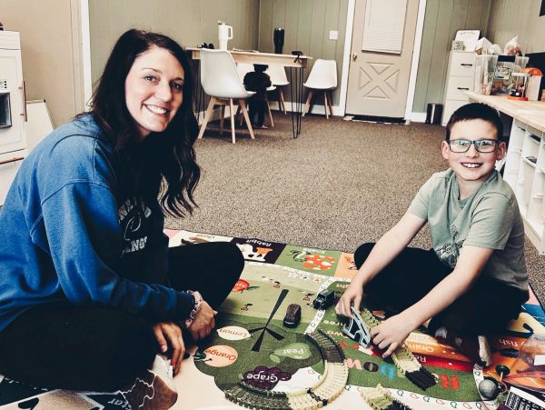 Woman and boy playing on a colorful mat indoors.