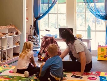 A serene landscape featuring a lake surrounded by mountains and a clear blue sky.