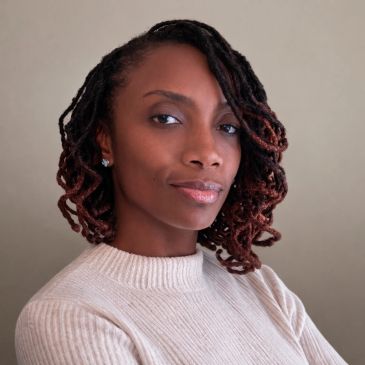 Confident woman with styled dreadlocks wearing a beige sweater.