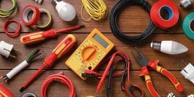 Various electrical tools and wires arranged on a wooden surface.