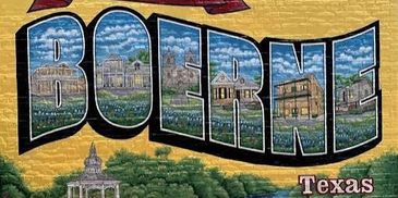 Mural saying Greetings from Old Town Boerne Texas on brick wall.