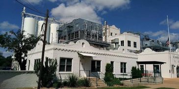 Industrial white building with tanks and clear blue sky.
