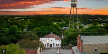 Sunset over Gruene with water tower and historic buildings.