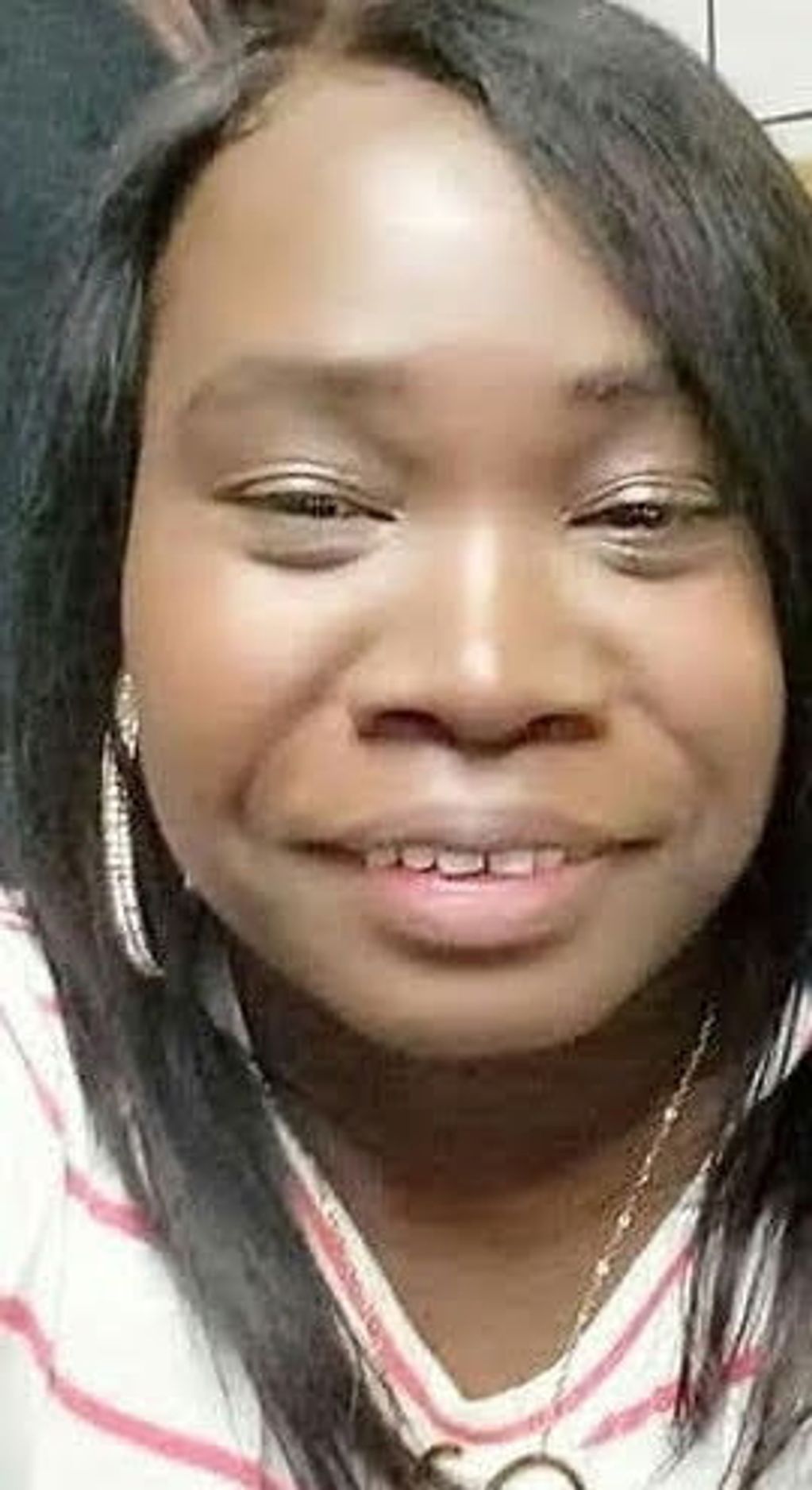 Close-up of a smiling woman with dark hair and striped shirt.