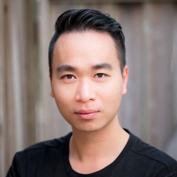 Portrait of a young man with slicked-back hair and a black shirt.