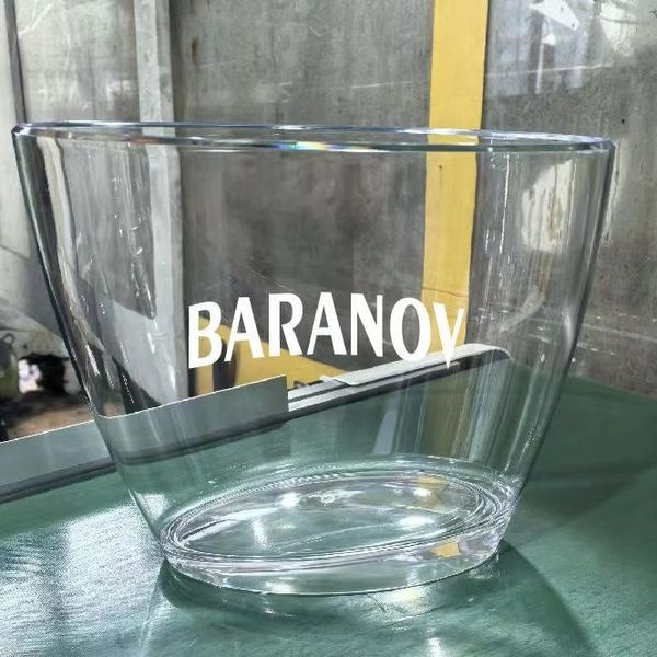 Clear glass bowl with 'BARANOV' printed on it, placed on a green surface.
