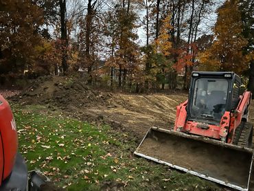 A bulldozer in a forest clearing during autumn.