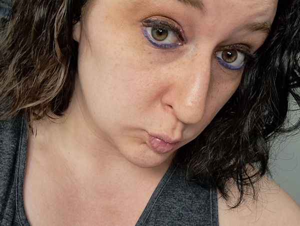 Close-up selfie of a woman with purple eyeliner.