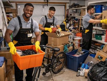 Three men in gloves and overalls sorting and packing items in a cluttered storage space.