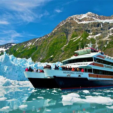 Tour boats near a glacier with snow-capped mountains in the background.