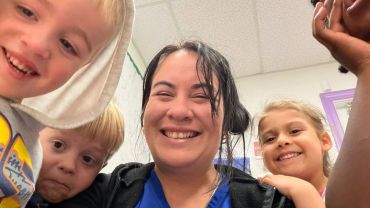 Smiling woman with children in a classroom.