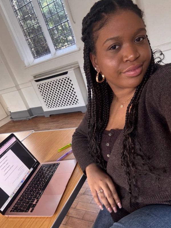 Woman taking a selfie by a laptop in a cozy room.